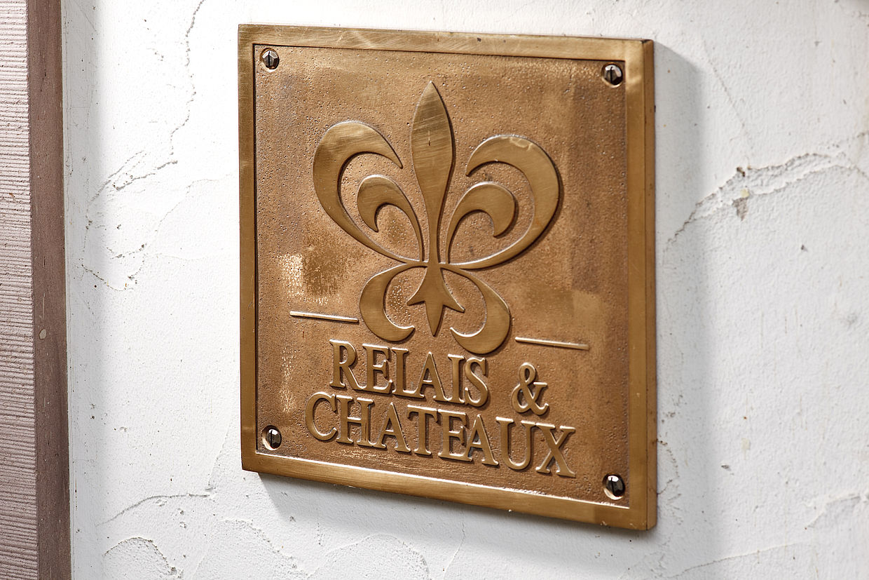 Goldene Platte mit dem Logo von Relax und Chateau an der Wand