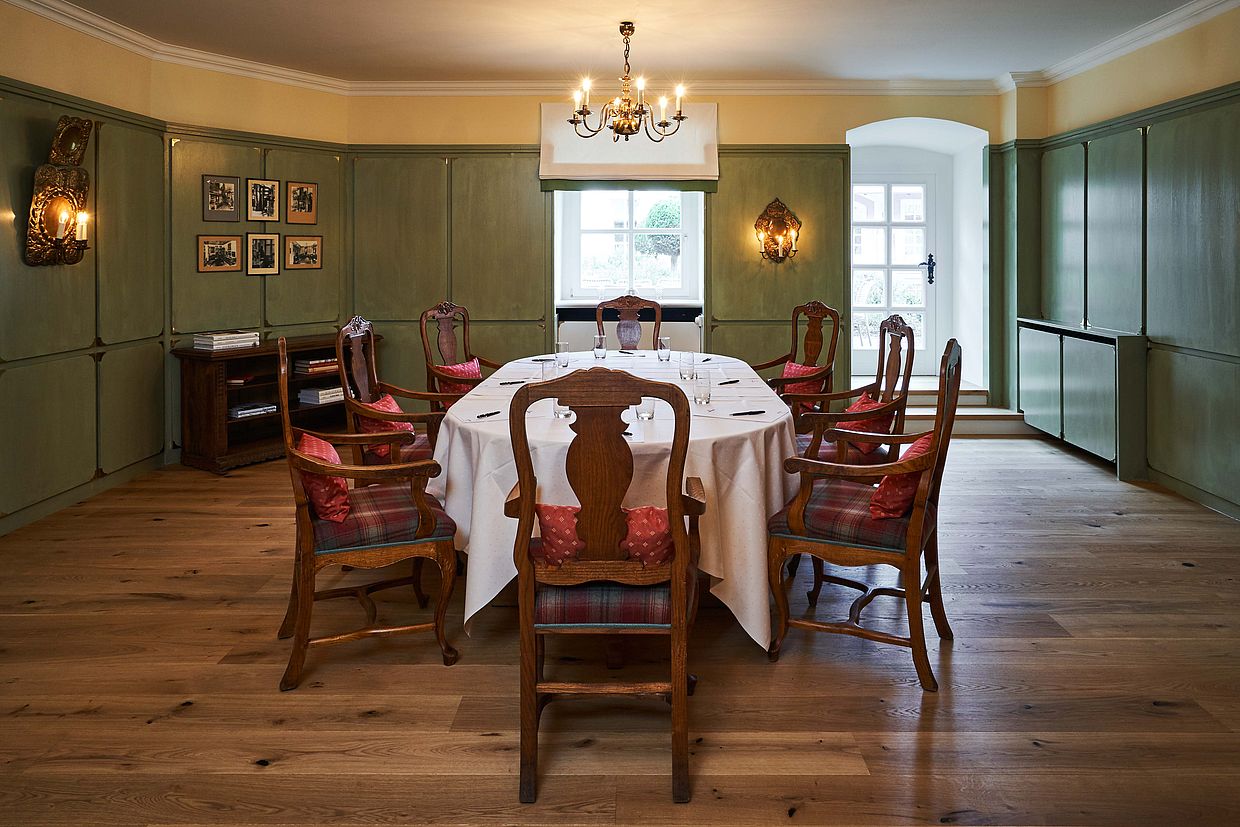 Holzstühle um einen ovalen Tisch, der für das Abendessen gedeckt ist im Danziger Lachsstube Raum