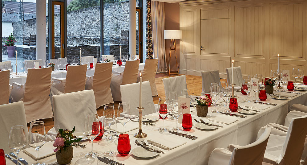 Mit weißen Tüchern bedeckte Tische und Stühle, dekoriert für ein Event im Hardenberg BurgHotel