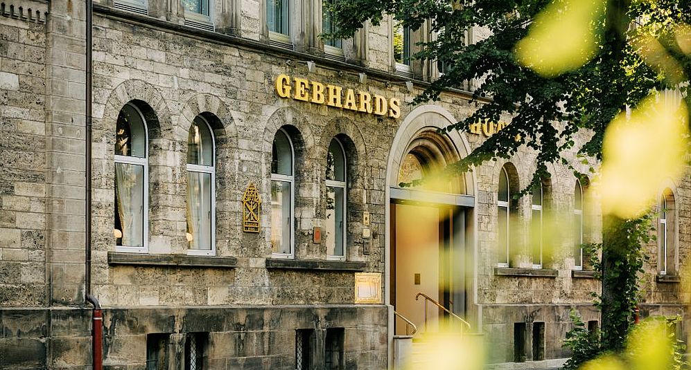 Nahaufnahme der Außenfassade des Gebhards Hotels umringt von Blattgrün