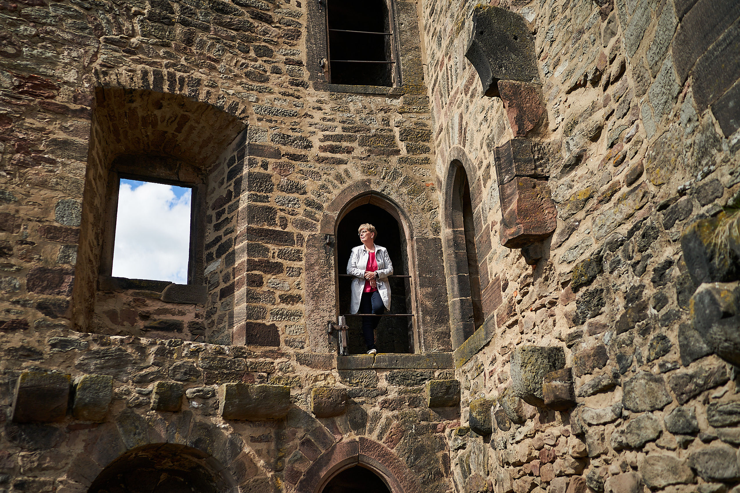 Eine Arbeiterin in ihrem Job in Nörten-Hardenberg steht auf der Burgruine und blickt in die Ferne
