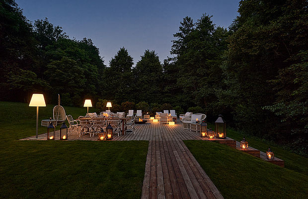 Beleuchtete Terrasse mit Sitzmöbeln bei Dämmerung