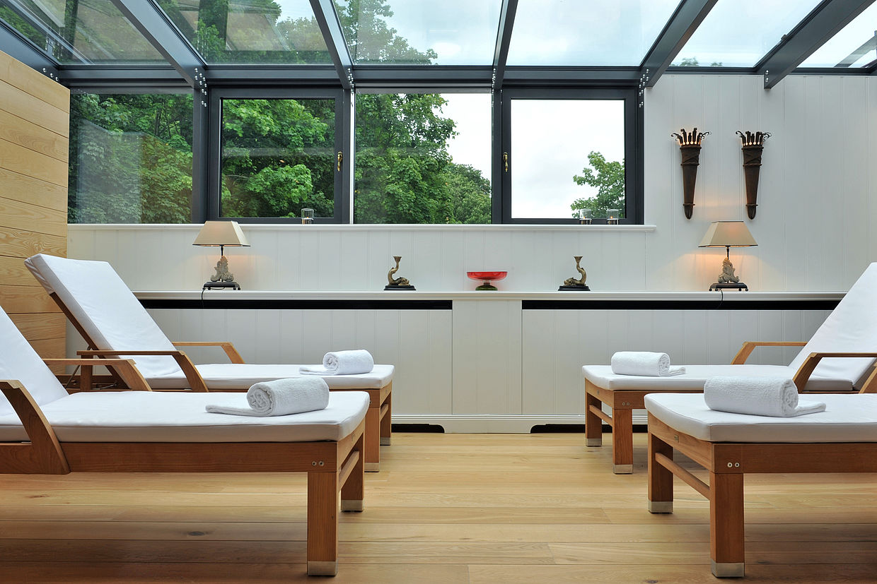 4 Holzstühle mit Handtüchern neben einem Fenster im Wellness-Bereich des Burghotels