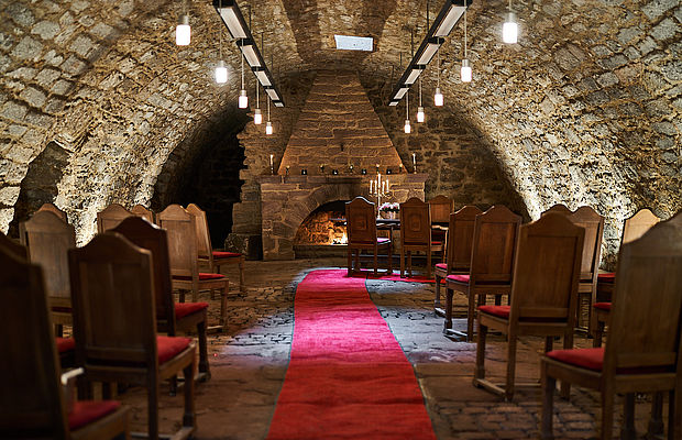 Festsaal für eine Hochzeit in Niedersachsen mit arrangierten Holzstühlen und einem roten Teppich